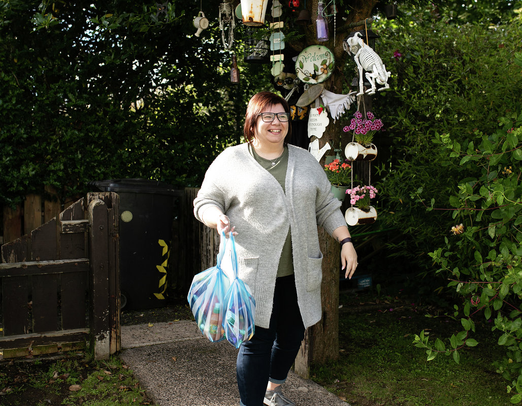 Smiling female shopping support volunteer carrying shopping bags